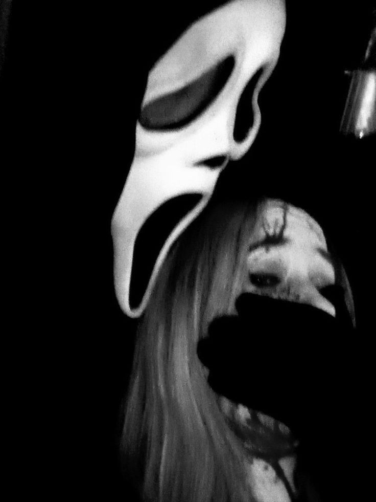 a woman wearing a white mask with long blonde hair in front of a black background