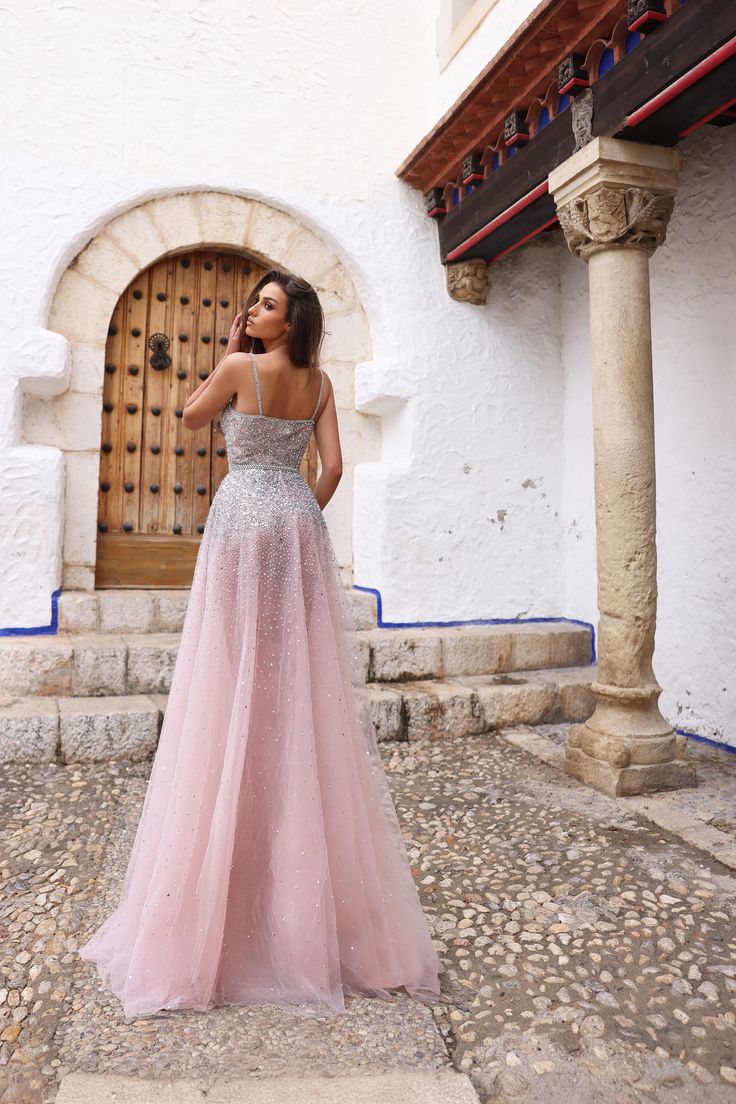 a woman standing in front of a door wearing a pink and silver dress