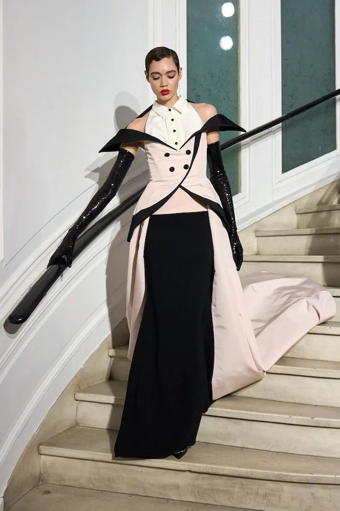 a woman in a black and white dress is standing on some stairs