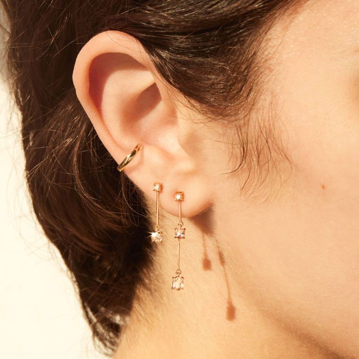 A woman with short brown hair wears two diamond drop earrings. Elegant Diamond Ear Cuff With Prong Setting, Formal Diamond Accents Ear Cuff, Formal Ear Cuff With Diamond Accents, Formal Diamond Accents Ear Cuff Fine Jewelry, Elegant Diamond Accents Ear Cuff For Anniversary, Elegant Cubic Zirconia Ear Cuff With Diamond Accents, Elegant Gold Cubic Zirconia Ear Climbers, Elegant Diamond Ear Cuff With Accents, Formal Fine Jewelry Cubic Zirconia Ear Cuff