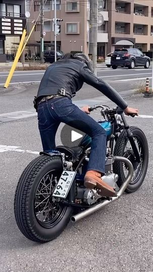 a man riding on the back of a motorcycle down a street