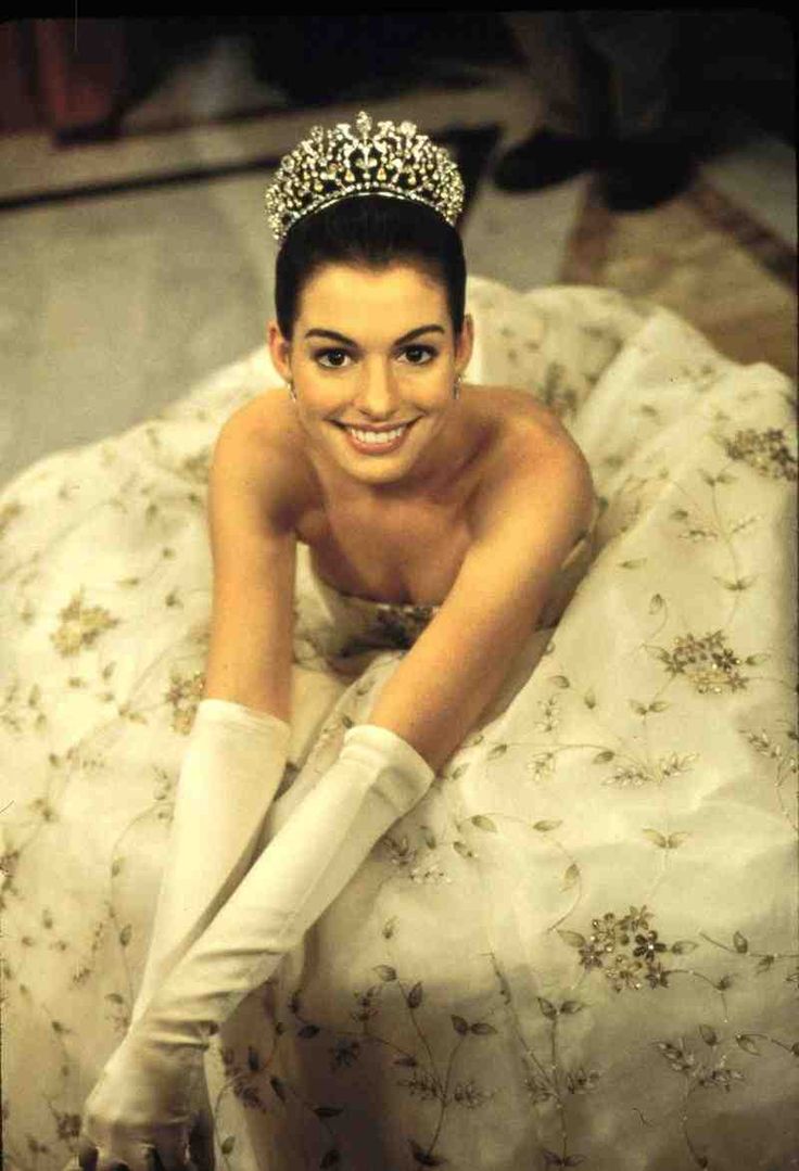 a woman wearing a tiara and gloves laying on a bed