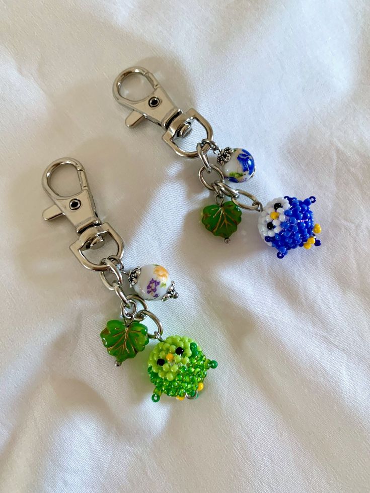 two key chains with charms attached to them on a white cloth covered tablecloth,