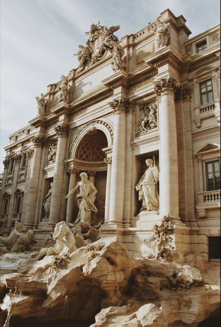 an ornate building with statues and fountains in front