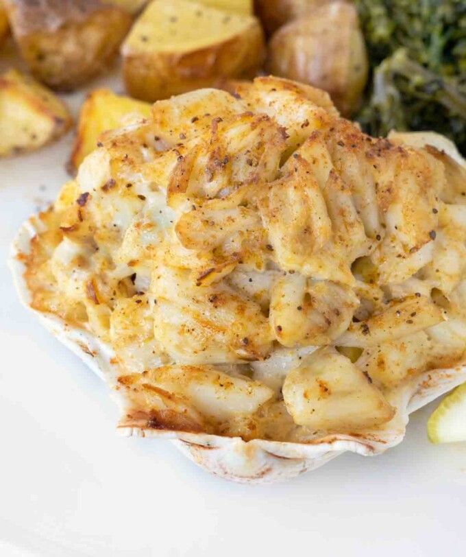 some food is on a white plate with potatoes and broccoli next to it