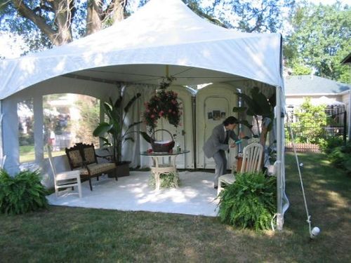 a white tent with chairs and trees in the background