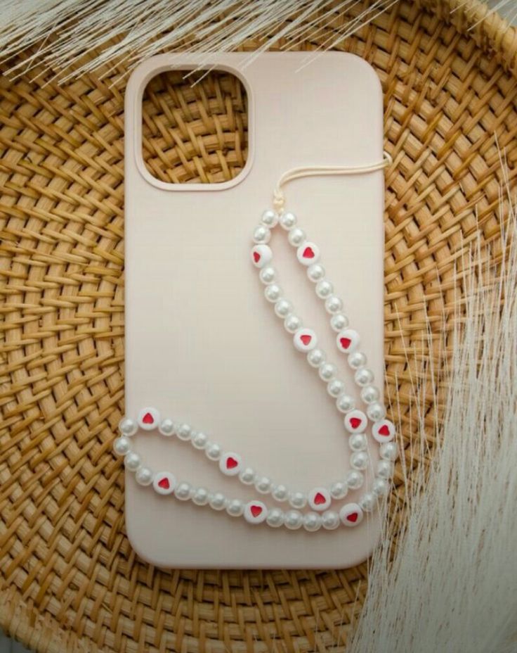 a cell phone case with pearls and red hearts on it sitting on top of a wicker basket