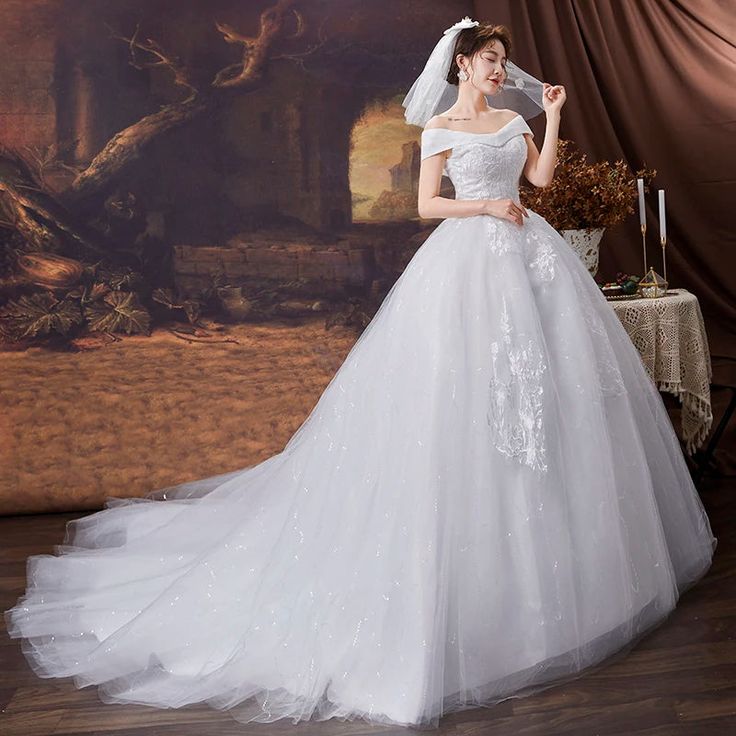 a woman in a white wedding dress standing on a wooden floor next to a painting