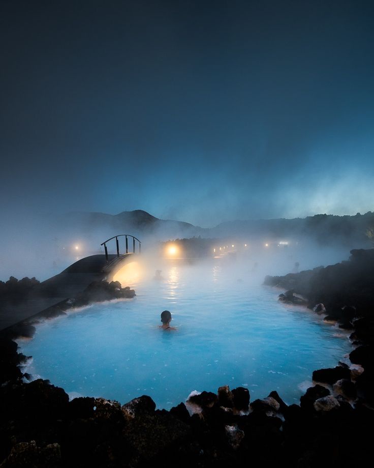 a man is swimming in the blue lagoon at night