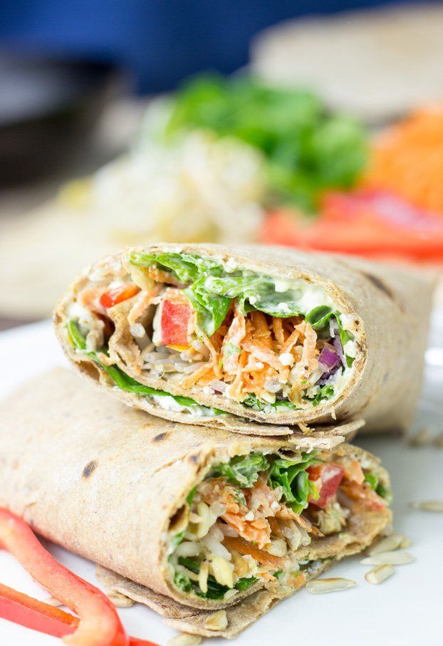 two wraps filled with meat and veggies on top of a white plate next to vegetables