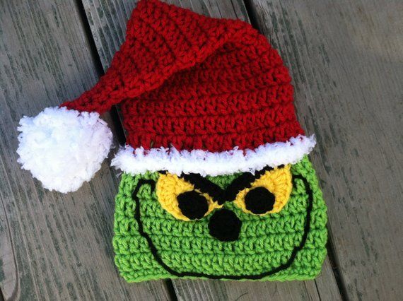 a crocheted hat with a grin face on it sitting on top of a wooden table