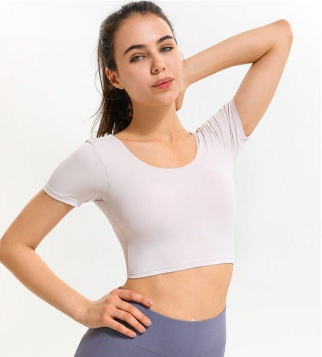 The EMES SHOP shirt details a low scoop backwithshortsleeves and a body hugging fit. Designed with crossing straps in the back. this classic. simple. and comfortable top will transform the way you perceive active wear.MATERIAL:78% Nylon 22% SpandexMEASUREMENTS:X-Small : 0-2 Waist: 23.5-25 in Chest: 31.5-33 inSmall : 4-6 Waist: 25-26.5 in Chest: 33-34.5 inMedium : 6-8 Waist: 26.5-28 in Chest: 34.5-36 inLarge : 8-10 Waist: 28-29.5 in Chest: 36-37.5 in Solid Top With Built-in Bra And Scoop Back, Sports Tops With Built-in Bra And Scoop Back, Summer Tops With Medium Support And Short Sleeves, Fitted Short Sleeve T-shirt For Yoga, Seamless Short Sleeve T-shirt For Gym, Compression Scoop Neck Top With Built-in Bra, Sporty Compression Scoop Neck Top, Solid Color Compression Scoop Neck Top, Solid Color Compression Top With Scoop Neck