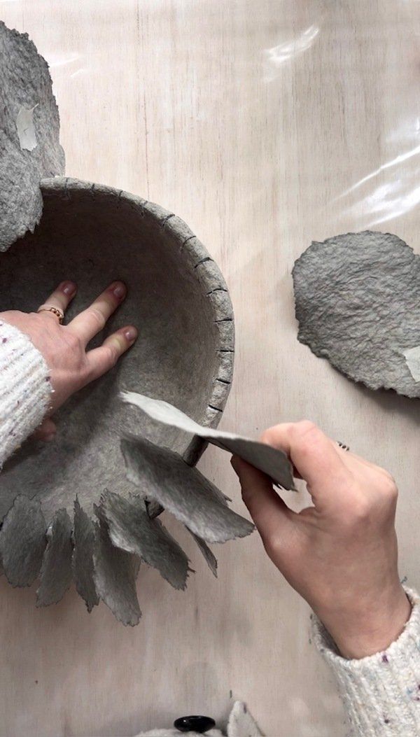 someone is using scissors to cut out the leaves on a paper mache bowl that they are holding