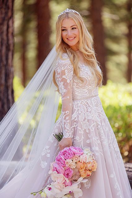 a beautiful blonde woman in a wedding dress holding a bouquet and posing for the camera