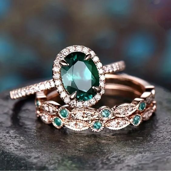 two wedding rings with green and white stones