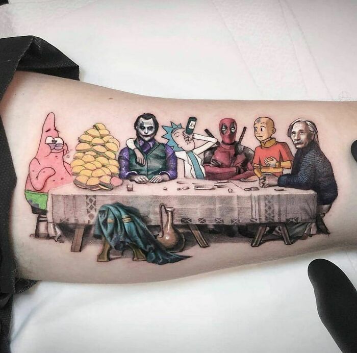 a person with a tattoo on their arm that has an image of people sitting at a table