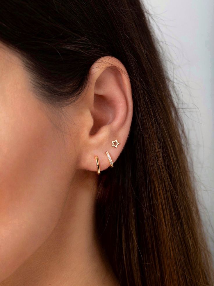 a woman's ear with two small gold stars on the top and one diamond in the middle