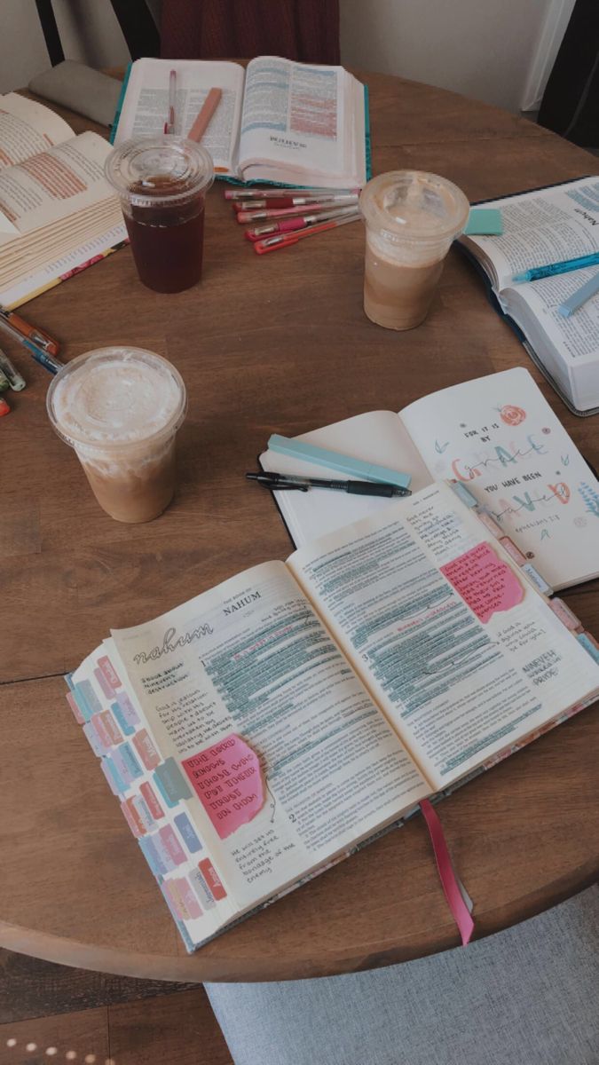 an open book sitting on top of a wooden table next to a cup of coffee