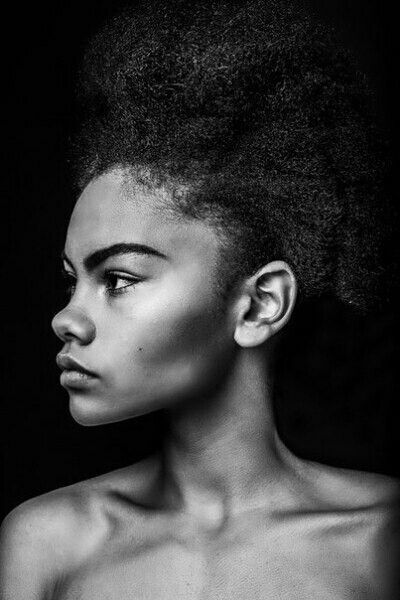 a black and white photo of a woman with an afro hairdow looking off to the side