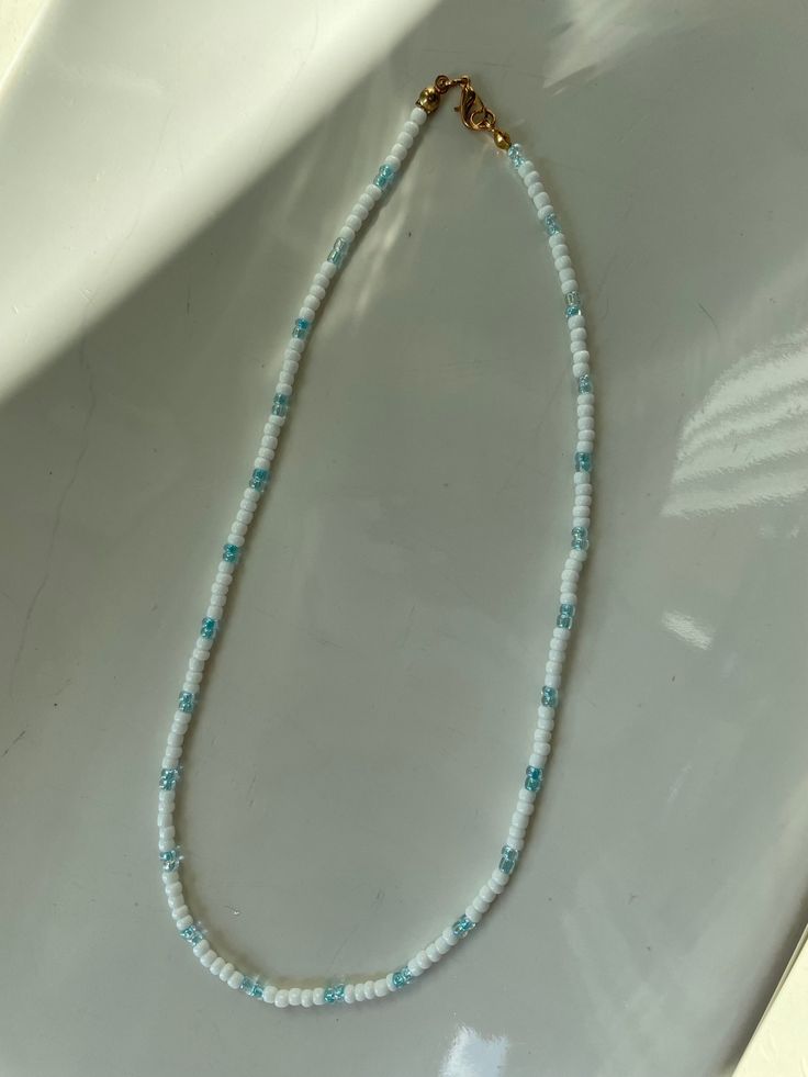 This is a adorable, handmade blue and white seed bead necklace. It has a clasp but the clasp is NOT waterproof, i would recommend not wearing it in water! measurements are in one of the photos on the listing, and so is how it looks like on. it comes with 2 stickers and a ring for free! Bohemian Summer Jewelry With Letter Beads, Casual Turquoise Jewelry With Tiny Beads, White Bohemian Beads For Everyday, Handmade Necklaces For Summer Beach Parties, Beaded Trendy Jewelry For Beach Season, Trendy Beaded Jewelry For Beach Season, Casual Turquoise Necklace With Tiny Beads, Everyday White Beaded Necklaces, Dainty Strand Jewelry For The Beach