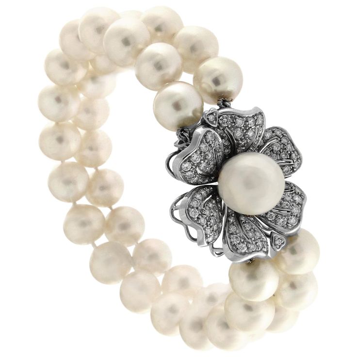 This breathtaking bracelet from the Flower Garden Collection captures elegance in every detail. It features two refined strands of luminous pearls, each complemented by a delicately crafted floral clasp adorned with 91 sparkling diamonds. The central pearl, with a 12mm diameter, adds a focal point of sophistication to this masterpiece. Gold: 18K, total weight 11 grams Diamonds: 91 stones totaling 3.03 carats, with exceptional clarity and sparkle Pearl Diameter: 12mm Stamp: 750 Exquisitely crafte Vintage Gold Bracelet, Gems Bracelet, Chic Bracelet, White Gold Chains, Flower White, White Gold Bracelet, Pearl Set, Gold Bracelet Chain, Pearl Diamond