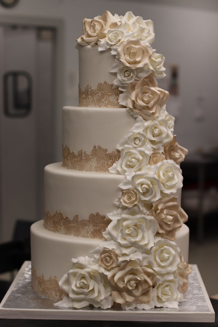 a three tiered wedding cake with white and gold flowers