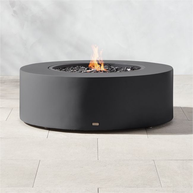 an outdoor fire pit sitting on top of a white tile floor next to a wall