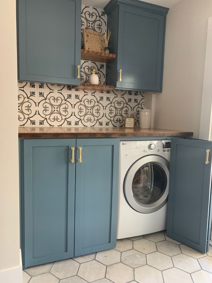 a washer and dryer in a small room with blue cupboards on the wall