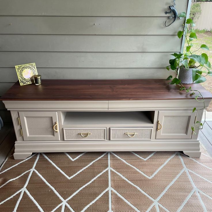 a tv stand sitting on top of a wooden floor next to a wall with a potted plant