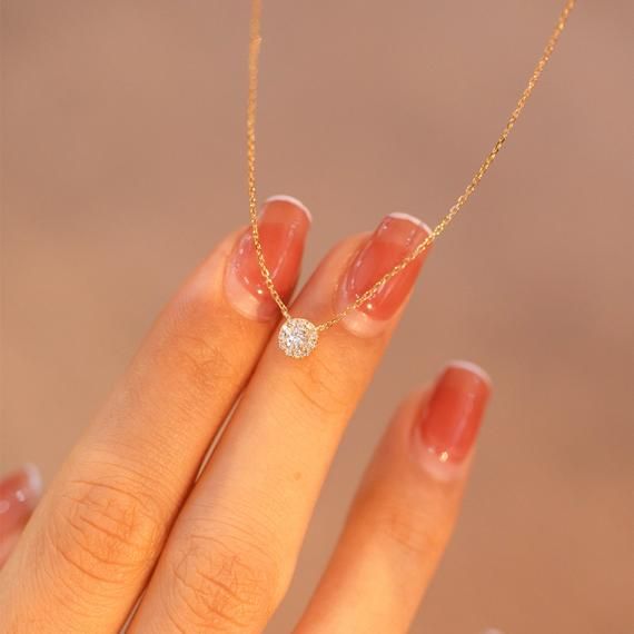 a woman's hand with a diamond ring on it and a gold chain necklace