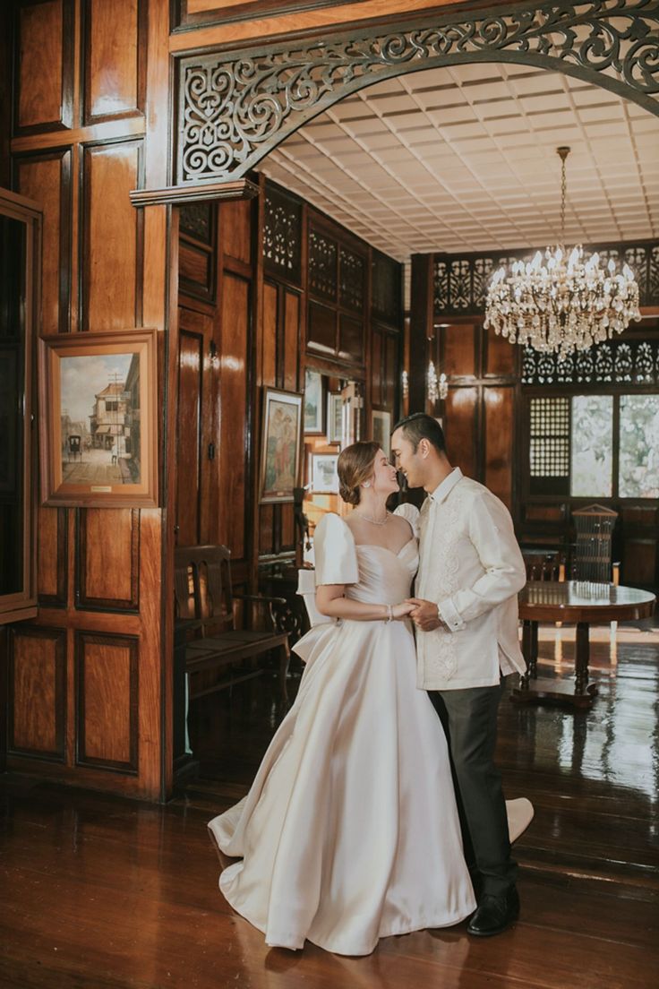 a bride and groom standing in front of a chandelier