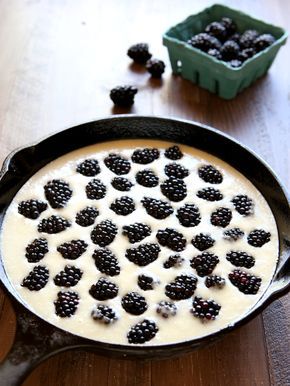 a pan filled with blackberries on top of a wooden table