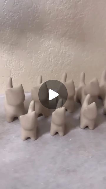 a group of clay elephants standing next to each other on top of a white surface