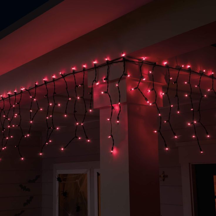 some red lights are hanging from the side of a house