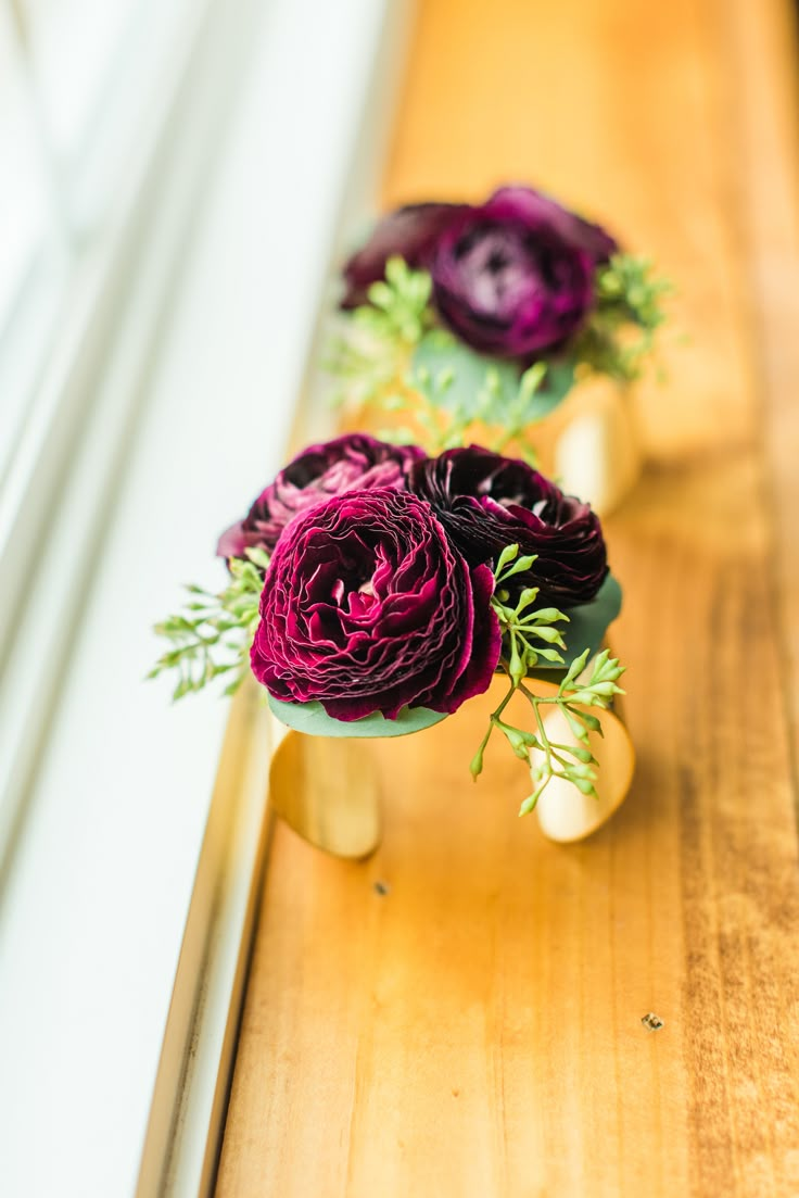 three purple flowers sitting on top of a wooden table