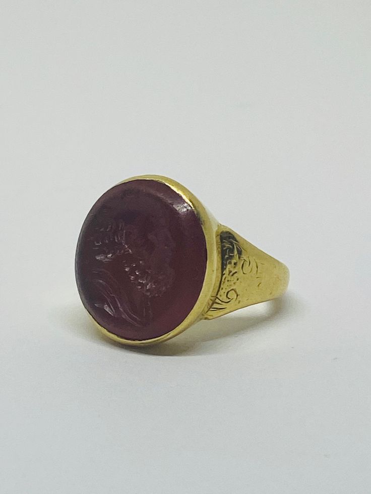 "This is a vintage 18K (high-karat) yellow gold Cameo-design statement ring. Definition of a \"cameo\": a piece of jewelry, typically oval in shape, consisting of a portrait in profile carved in relief on a background of a different color. Material(s): 18K yellow gold + unidentified material (cameo) Total weight: 12.2 grams Flaws (if any): None to mention Marking(s): \"18ct\" (translating to 18K gold) Measurements: The face of the ring measures 17.9 millimeters in height by 5.8 millimeters in wi Formal Gold Cabochon Signet Ring, 14k Gold Ruby Cabochon Ring, Gold Ruby Ring With Cabochon In 14k Gold, Classic Yellow Gold Signet Ring With Cabochon, Formal Yellow Gold Signet Ring With Oval Cabochon, Gold Cabochon Domed Rings, Victorian Gold Cameo Rings, Formal Domed Signet Ring With Cabochon, Gold Heirloom Signet Ring With Cabochon