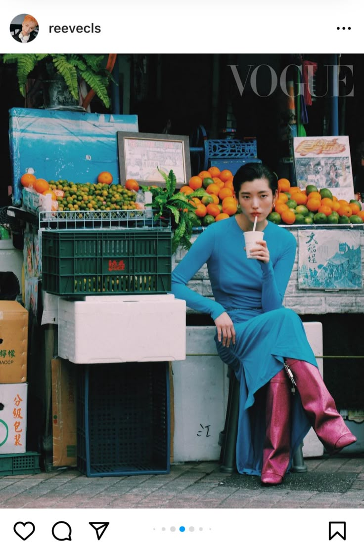 a woman sitting on a bench in front of a fruit stand