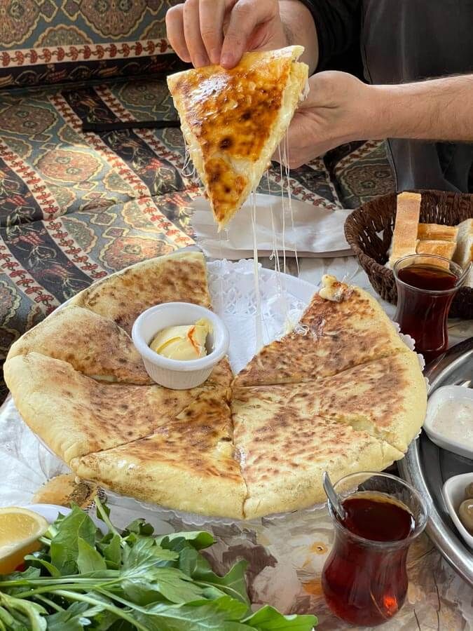 a person is eating pizza on a table with other food and drinks around it,