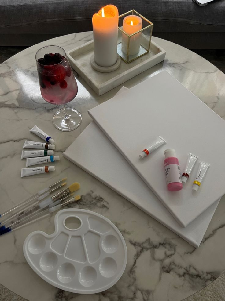 a marble table topped with candles and art supplies