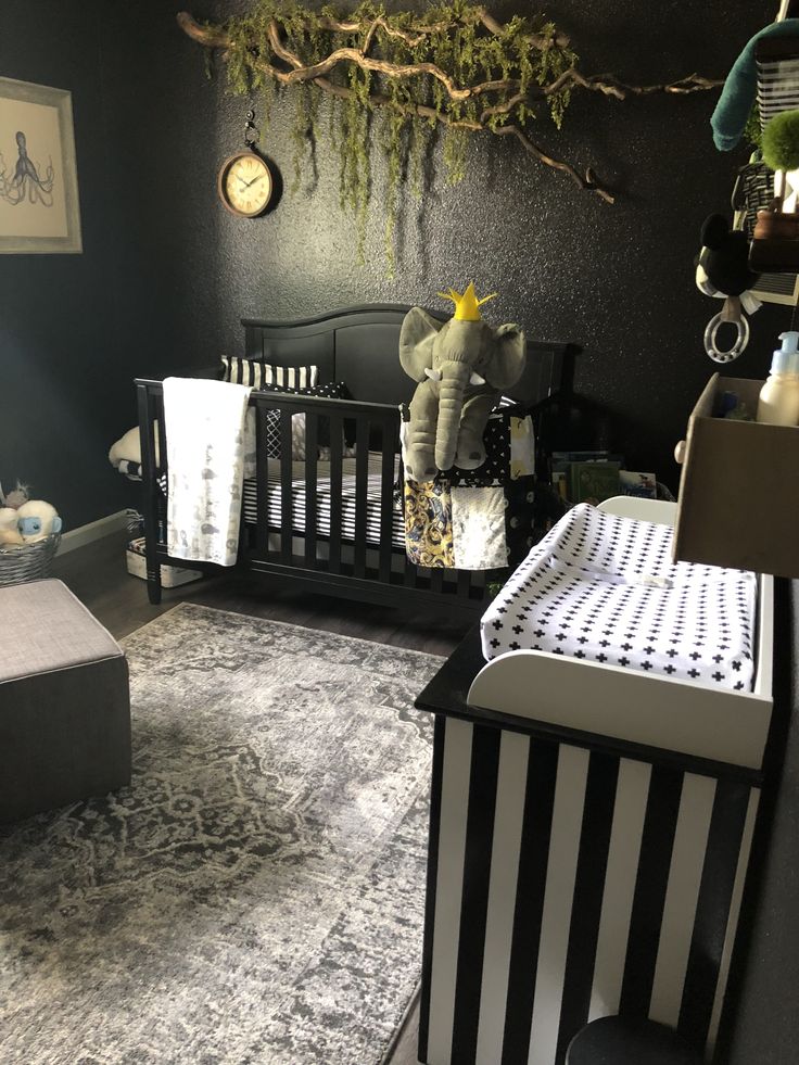 a baby's room with black walls, white and gray furniture and an elephant crib