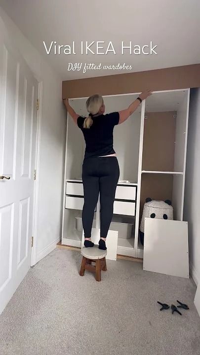 a woman standing on top of a wooden stool in front of a white closet door