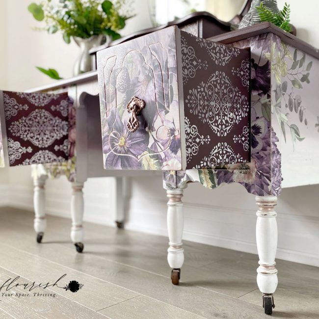 an ornately decorated table with drawers on wheels in front of a mirror and flowers