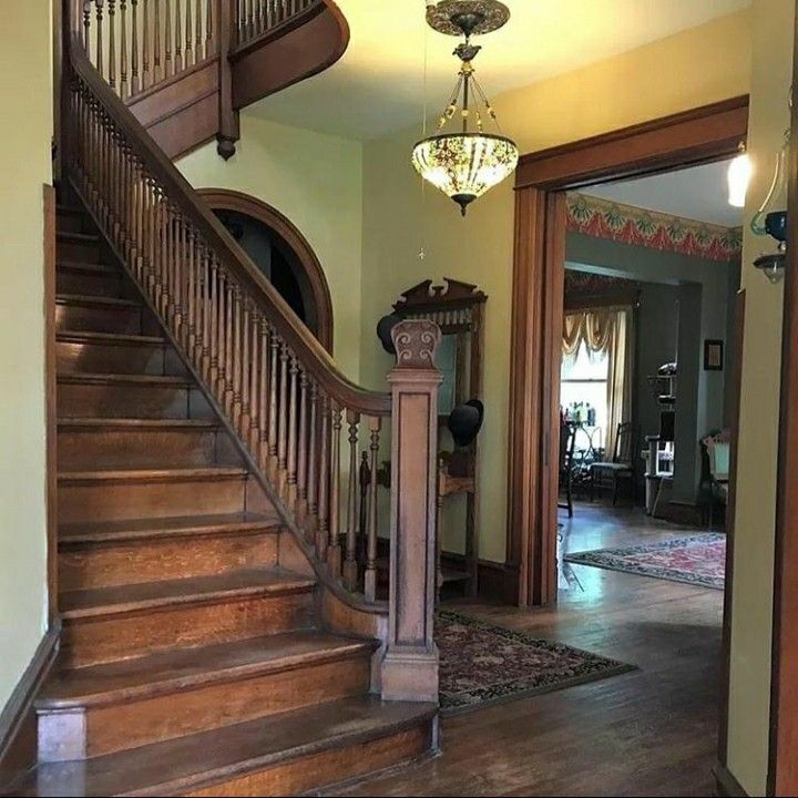 a wooden staircase leading up to a living room with a chandelier above it