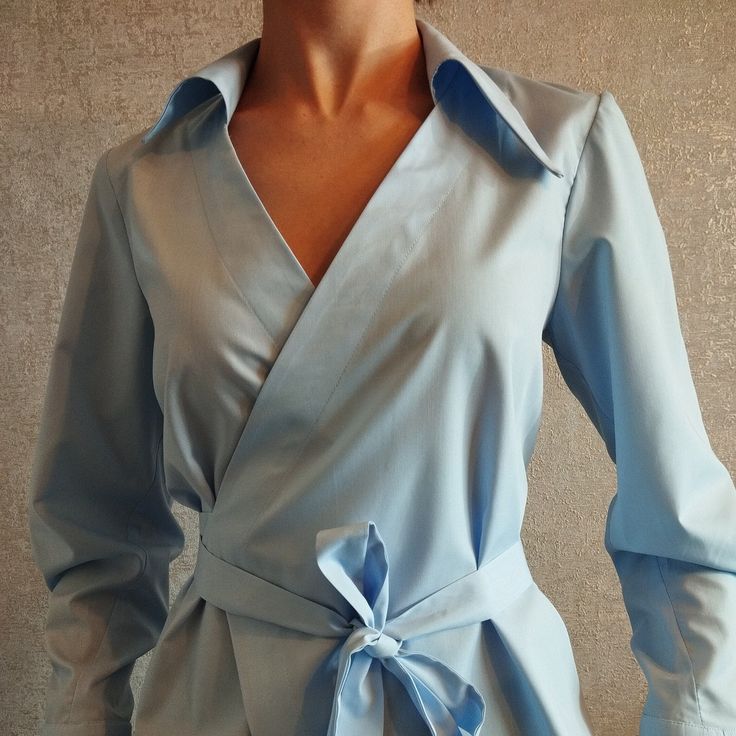 Introducing our stunning blue modern blouse wrap belt with an asymmetric collar. This unique and effortlessly chic piece is perfect for adding a touch of contemporary elegance to any outfit. The wrap design creates a flattering silhouette, while the asymmetrical collar adds a stylish twist. Made from high-quality materials, this blouse is both comfortable and durable. Whether you're heading to the office or out for a night on the town, this versatile blouse is sure to turn heads. Pair it with yo Spring Party Blouse With Tie Waist, Chic Blouse With Lapel Collar, Chic Business Casual Blouse With Lapel Collar, Chic Long Sleeve Top With Tie Waist, Chic Long Sleeve Wrap Top For Party, Elegant Belted Blouse For Work, Elegant Summer Blouse With Tie Waist, Modern Long Sleeve Blue Blouse, Elegant Wrap Blouse For Summer