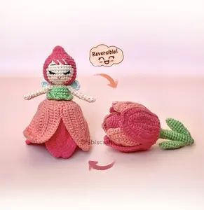 two crocheted dolls sitting next to each other on top of a pink surface