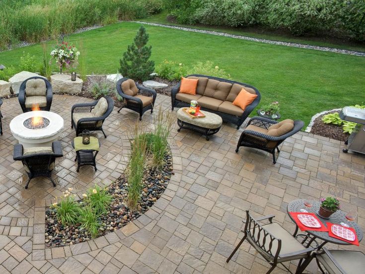 an outdoor living area with patio furniture and fire pit in the center, surrounded by green grass