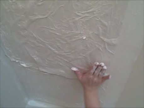 a person's hand reaching up to paint on the wall in a bathtub