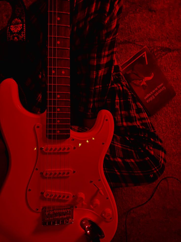 a red electric guitar sitting on the ground