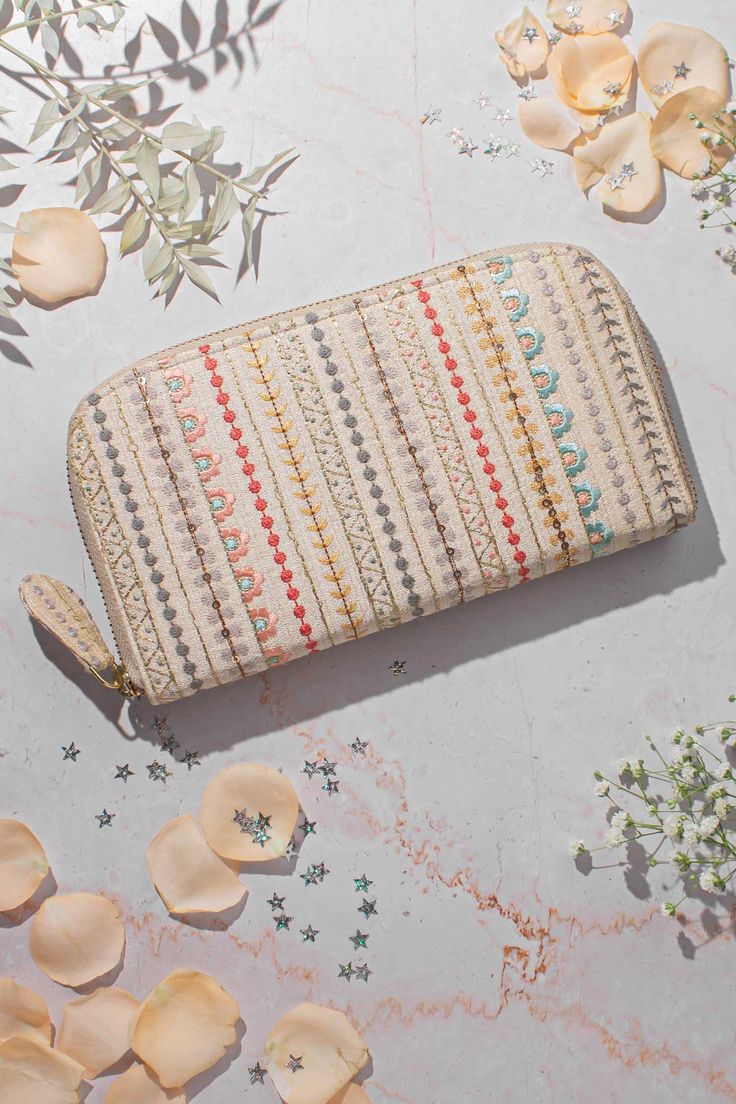 a small purse sitting on top of a table next to flowers and petals in the background