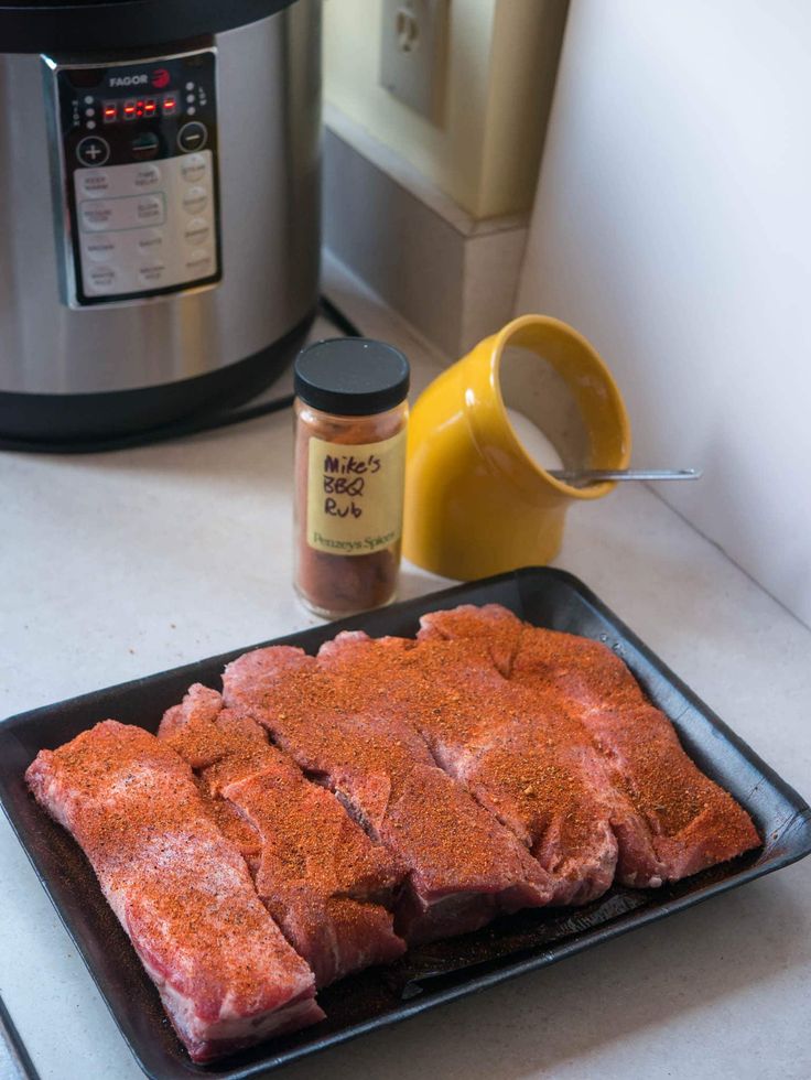 some meat is on a plate next to an instant pot roaster and seasoning